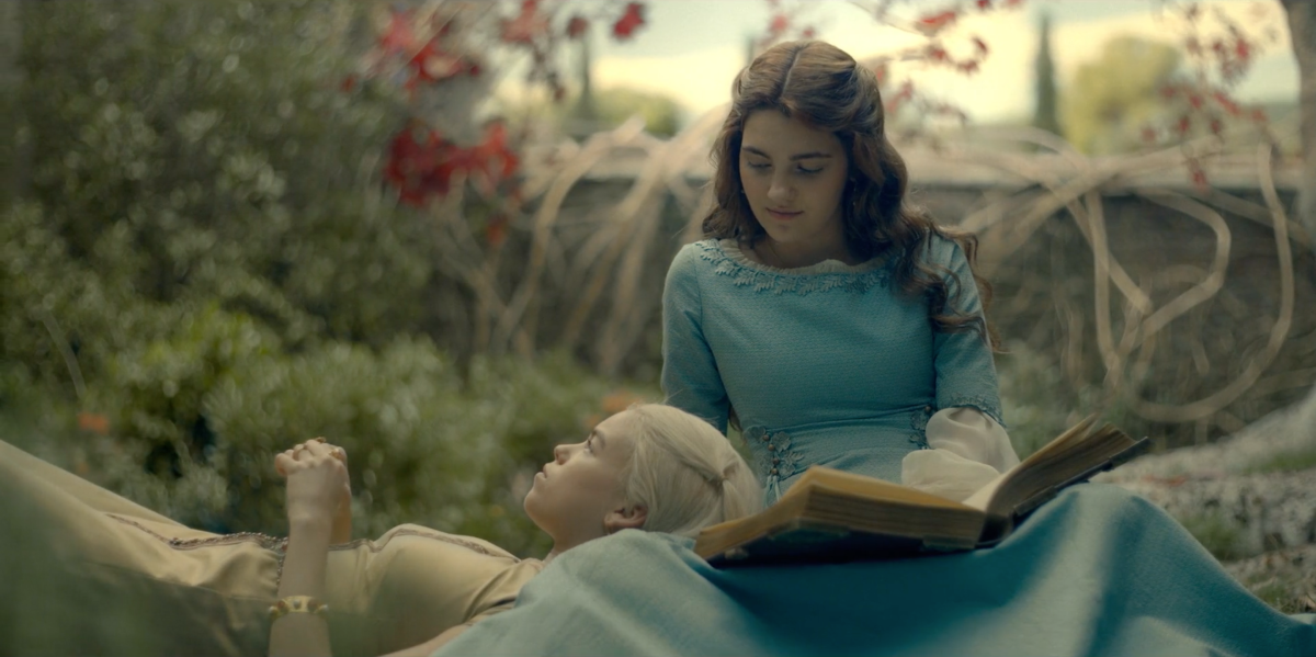 Rhaenyra Targaryen and Alicent Hightower lie on each other's lap as kids